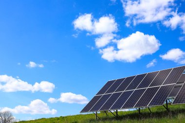 Açık havada çalışan bir güneş pili tesisi. Doymuş mavi bulutlu gökyüzünün arka planında fotoelektrik piller var. Güneş panelleri. Ekoloji, alternatif enerji kavramı