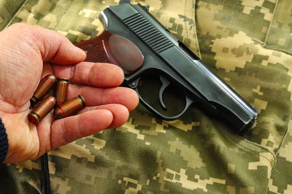 Firearms on military uniform. Top view of gun with bullets in palm. Military weapons of the USSR. A gun for defense or offense. The concept of military ammunition.