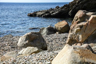 Güneşli bir yaz gününde, denizin taşlı kayalık kıyılarında. Kayaların ve Athos Dağı 'nın güzel manzarası. Yunanistan.