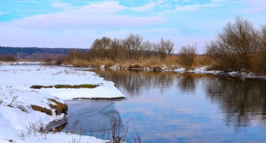 Güneşli bir kış gününde, küçük bir nehri olan karlı kış manzarası. Kışın donmuş nehir suyu. Anavatanın güzelliği. Ukrayna, Avrupa