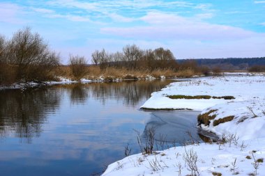 Güneşli bir kış gününde, küçük bir nehri olan karlı kış manzarası. Kışın donmuş nehir suyu. Anavatanın güzelliği. Ukrayna, Avrupa