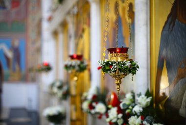 Bir çiçek çelengi ve ikonun önünde bir lambayla süslenmiş. Yanan bir lamba, bir Ortodoks kilisesindeki güzel bir şamdanın önünde kırmızı bir ampulde sallanan bir mum. Ortodoksluk kavramı
