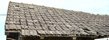 Batan güneşin ışınlarıyla kiremitlerle kaplı eski bir kil bina. Eskimiş malzemeler ve doku. Batı Ukrayna 'nın kırsal bölgesi.