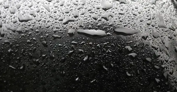 Sabah çiğ damlaları ya da vücut yüzeyine yağan yağmur damlaları, araba aynası. Sığ odak derinliği, makro.