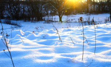 Karlı yamaçlı kış manzarası batan güneşin sahneyi koyu mavi tonlarda beyaz karla boyadığı yer..
