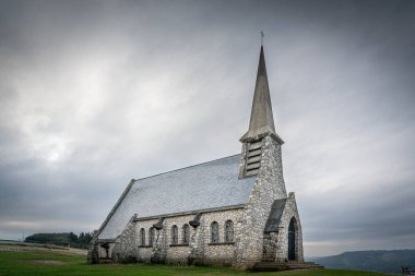 Fransa 'nın Normandiya kıyısındaki eski büyük tuğlalardan oluşan eski bir kilise gün ışığında gri bir gökyüzünün altında.