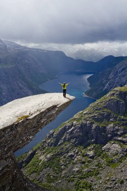 Trolltunga kayası üzerinde duran kız (Trol Dili Kayası) ve Norveç dağ manzarası ile fotoğraf çeker