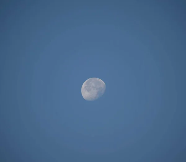 White moon in the daytime against blue background