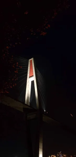 Skytrain bridge with concrete and red being lit at night in British Columbia