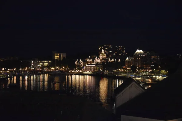 Light reflects off the water by Parliament and museum in downtown Victoria British Columbia\'s Inner Harbour