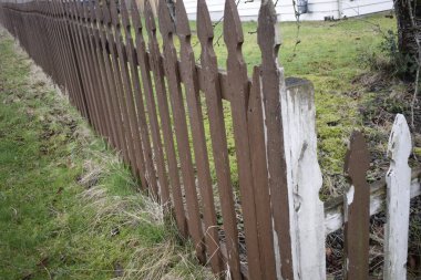 Kahverengi ve beyaz çitli, boyalı ve çimenli.
