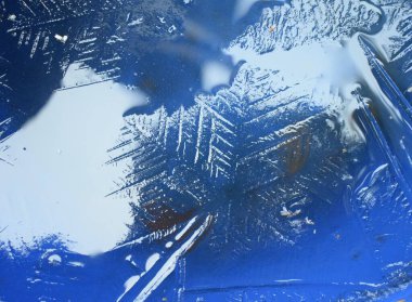 Donmuş suda, altında yapraklar ve yansıtan ışık olan büyük doğal kar taneciklerinin desenlerini kapatın.