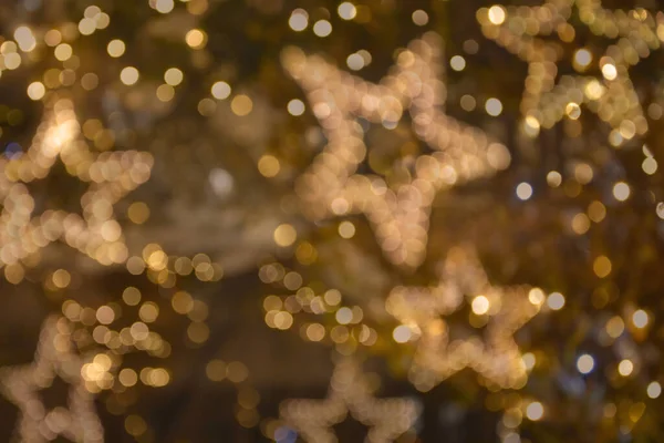 Golden christmas stars lights blur background stock images. Gold holiday blurred bokeh wallpaper horizontal stock photo. Christmas lights and stars defocused stock photo images