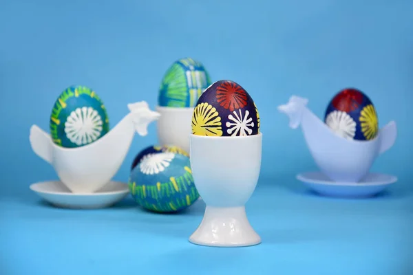 Beautiful hand painted easter eggs in ceramic egg cup holder stock images. Easter decoration with colored eggs on a blue background stock photo. Traditional unique easter eggs images