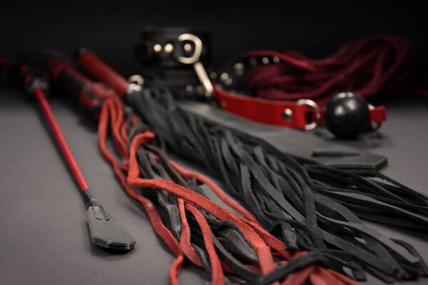 Leather whip flogger sex toys on a dark background stock photo images. Set of erotic toys for BDSM stock photo. Adult sex toy, flogger, ball gag, handcuffs, rope stock images