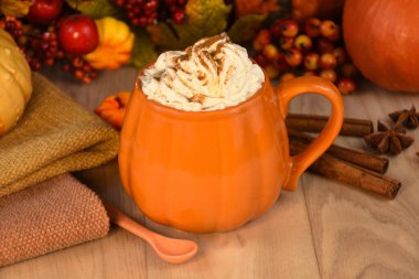 Portakallı kahve kupası, ahşap arka planda kremalı fotoğraf resimleri. Sonbahar sıcacık arkaplanı, kremalı sütlü kahve içeceği ve balkabağı stok fotoğrafı. Balkabağı aromalı latte natürmort