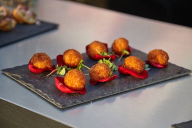 Lezzetli kızartılmış atıştırmalıklar gül yaprakları ve yeşilliklerle süslenmiş bir tabakta güzelce sunuluyor.