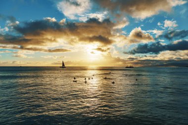 Gün batımında, bireylerin bir araya geldiği okyanusta yüzerken, su, bulut ve doğal manzara ile çevrili olarak görülür. Gün batımının sıvı ufuk çizgisine düşmesiyle gök kararır.