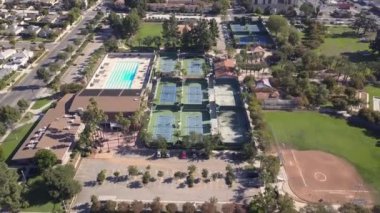 Bir kuş bakışı, birden fazla tenis kortu, büyük bir havuz ve bir beyzbol sahası olan canlı bir spor kompleksi sergiliyor.