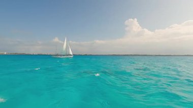 Bir yelkenli, büyüleyici turkuaz okyanusta zarif bir şekilde süzülür, büyüleyici hava açılarından yakalanır, açık denizlerdeki macerayı somutlaştırır.