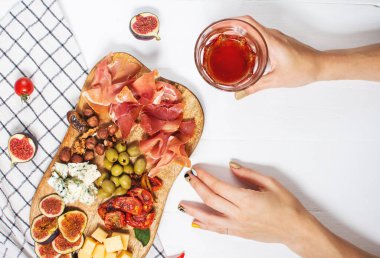 Jambonlu Antipasto tabağı, prosciutto, mavi peynir, kurutulmuş domates, incir ve zeytinli ahşap bord. Üst Manzara. Kadın elleri.
