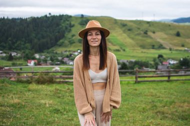 A young girl enjoys the beauty of nature, looking at the mountains in the village. Adventure journey through the Carpathians, Ukraine. free lifestyle