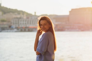 Nehir kenarındaki kız gökyüzüne karşı eğleniyor. Yaz titreşimleri.