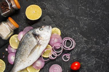 Siyah taş masada çiğ dorado balığı ve pişirmek için gerekli malzemeler. Kopyalama alanı olan üst görünüm