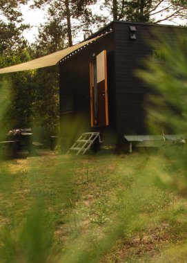 Bir sonbahar ormanının arka planında ahşap kaplamalı modüler çerçeve tipi tekerlekli bir daire. Yaşam ve turizm için mobil ekolojik alan