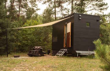 Bir sonbahar ormanının arka planında ahşap kaplamalı modüler çerçeve tipi tekerlekli bir daire. Yaşam ve turizm için mobil ekolojik alan.