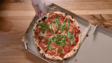 Bir dilim sıcak margarita pizza. İnsan eli, açık kutudan sıcak İtalyan pizzasından dilimler alıyor.