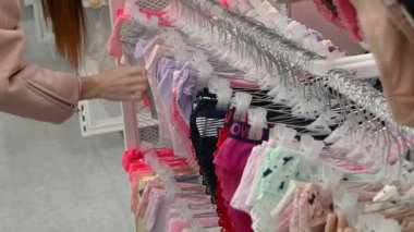 Elbise mağazasında iç çamaşırlı elbise askısı kadın elleri tanınmayan kadın kıyafetleri sınıflandırıyor müşteri butikte kıyafet seçiyor yeni bir şey satın alıyor indirimli satış indirimi.