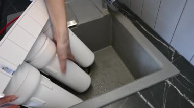 Mutfağa su filtresi koyan bir kadın. Su arıtma sisteminin kurulumu