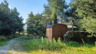 Kişisel küçük bir otel saunası. Tahta fıçı şeklinde mobil kompakt banyo. SPA, sakin ol. Kafkasyalı bir kadının ormanda yürüdüğünü gördüm.
