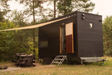 Bir sonbahar ormanının arka planında ahşap kaplamalı modüler çerçeve tipi tekerlekli bir daire. Yaşam ve turizm için mobil ekolojik alan