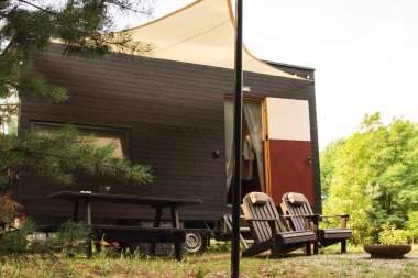 Bir sonbahar ormanının arka planında ahşap kaplamalı modüler çerçeve tipi tekerlekli bir daire. Yaşam ve turizm için mobil ekolojik alan