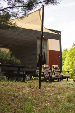 Bir sonbahar ormanının arka planında ahşap kaplamalı modüler çerçeve tipi tekerlekli bir daire. Yaşam ve turizm için mobil ekolojik alan