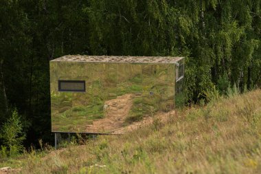 Yaz ormanının arka planındaki modüler çerçeve ayna evi. Yaşam ve turizm için mobil ekolojik alan.