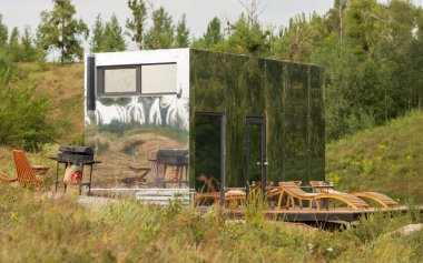 Yaz ormanının arka planındaki modüler çerçeve ayna evi. Yaşam ve turizm için mobil ekolojik alan