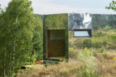 Yaz ormanının arka planındaki modüler çerçeve ayna evi. Yaşam ve turizm için mobil ekolojik alan.