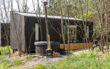 Ormandaki Ahşap Güverteli ve Izgaralı Modern Siyah Küçük Ev.