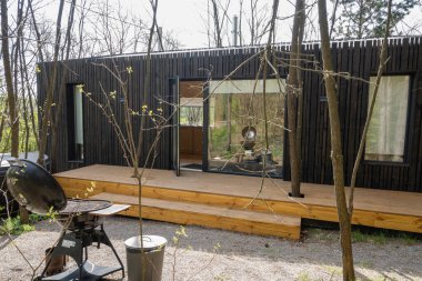 Ormandaki Ahşap Güverteli ve Izgaralı Modern Siyah Küçük Ev.