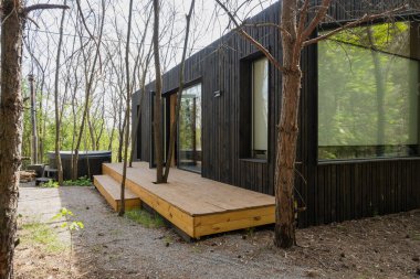 Ormandaki Ahşap Güverteli ve Izgaralı Modern Siyah Küçük Ev.