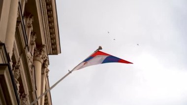 Sırbistan 'ın ulusal bayrağını sallıyor ve gökyüzü ağır çekimde seyrediyor. Belgrad, Sırbistan - 2 Nisan 2023.