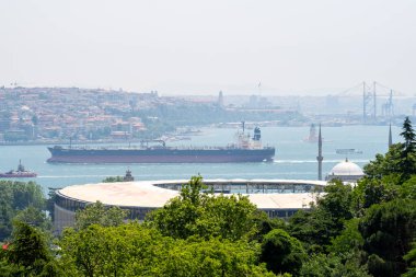Boğaz 'dan geçen bir kargo gemisi. Maiden 's Tower ve Besiktas Stadyumu. İstanbul, Türkiye - 20 Haziran 2023.