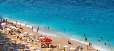 Akdeniz Kaputas Sahili 'nde yüzen insanların panoramik görüntüsü. Kaputas Plajı, Kas ve Kalkan arasında küçük bir plajdır. Antalya, Türkiye - 10 Temmuz 2023.