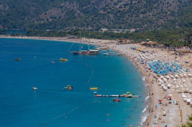 Oludeniz 'deki Belcekiz (Belcegiz) plajında güneşlenen ve yüzen turistlerin görüntüsü. Mugla, Türkiye - 10 Temmuz 2023.