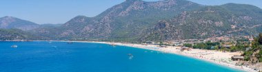 Belcekiz (Belcegiz) Sahili ve Oludeniz 'de (Mavi Göl) güneşlenen ve yüzen turistlerin panoramik manzarası. Mugla, Türkiye - 10 Temmuz 2023.