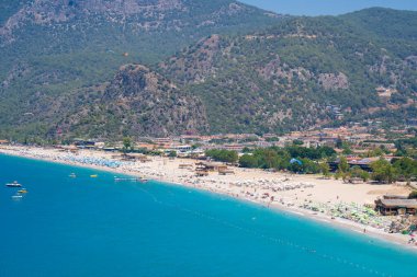 Oludeniz 'deki Belcekiz (Belcegiz) plajında güneşlenen ve yüzen turistlerin görüntüsü. Mugla, Türkiye - 10 Temmuz 2023.