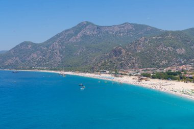 Oludeniz 'deki Belcekiz (Belcegiz) plajında güneşlenen ve yüzen turistlerin panoramik manzarası. Mugla, Türkiye - 10 Temmuz 2023.